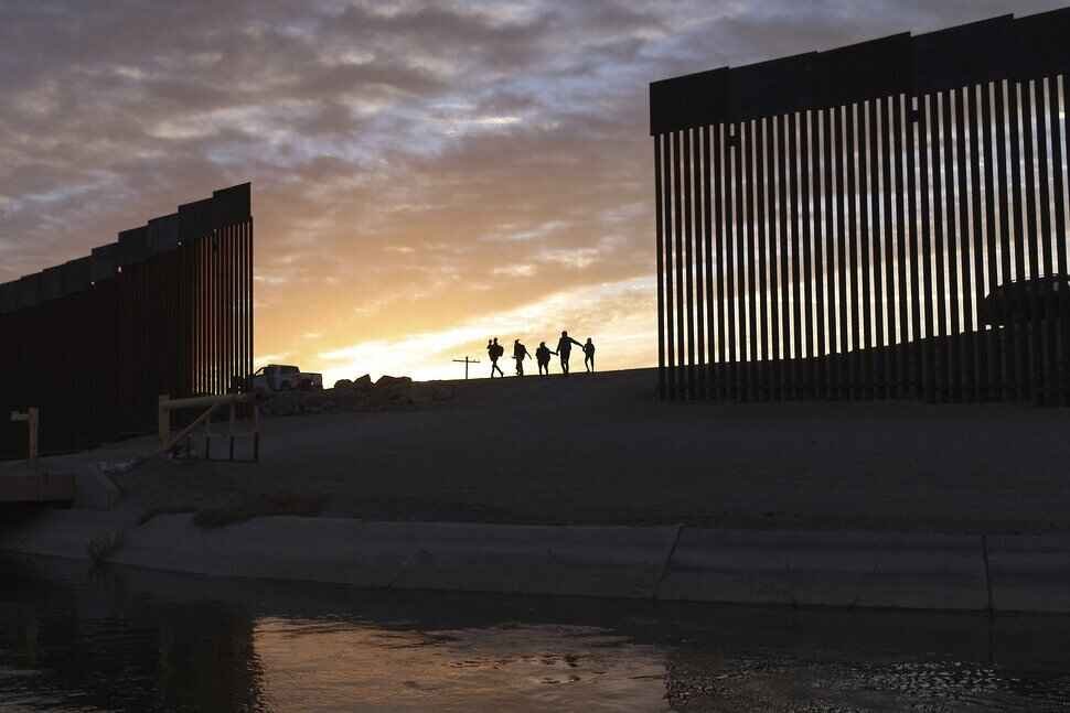 A family crosses across an unfinished part of the Border wall build by Donald Trump